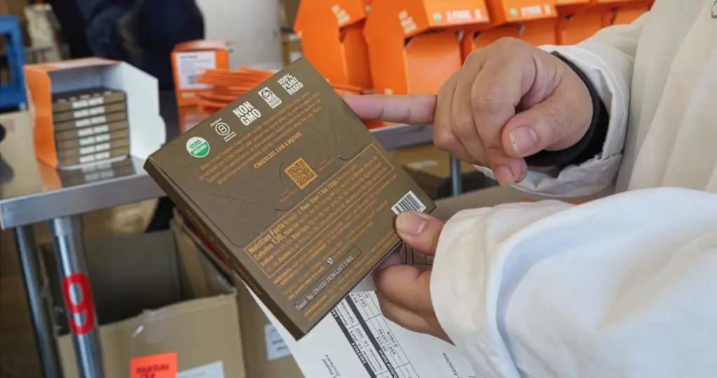 Hands holding organic product package showing USDA certification label and QR code.