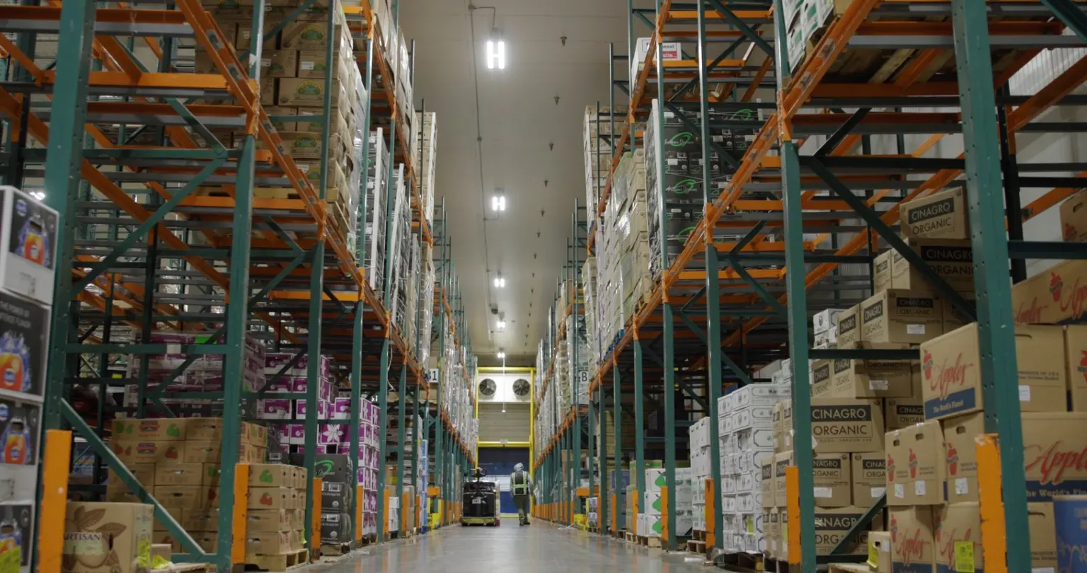 Warehouse aisle lined with tall racks of stacked organic produce boxes