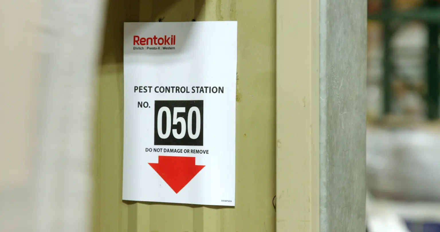 Numbered pest control station sign mounted on a support post inside a warehouse